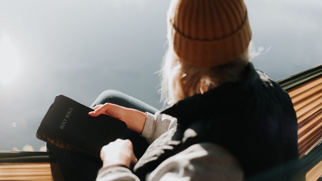 woman holding bible looking over lake