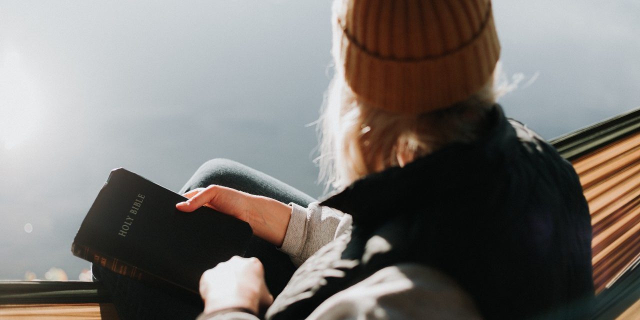 woman holding bible looking over lake