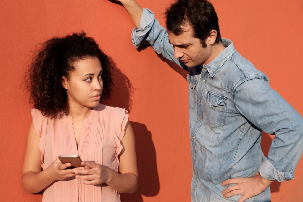 man looking at phone that woman is holding