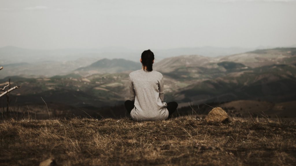 Woman sitting on cliff on a cloudy day