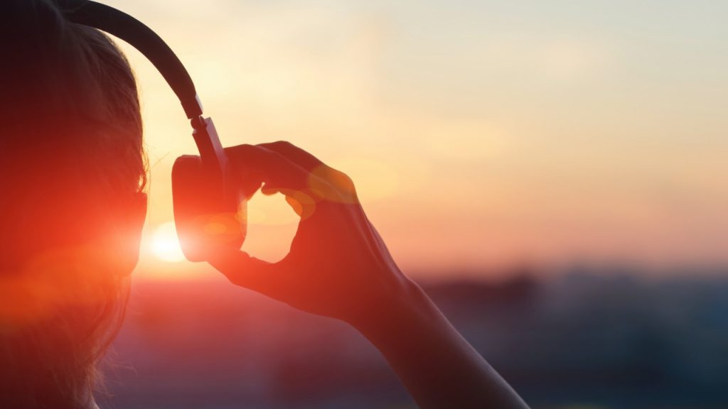 Person talking off headphones at the beach during sunset