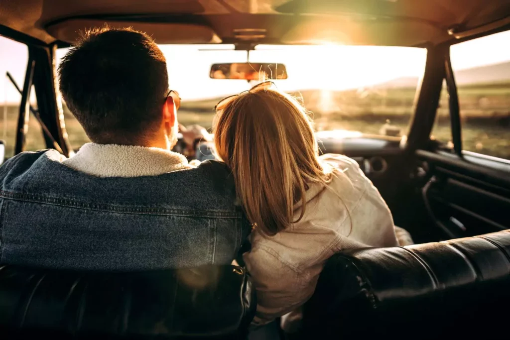 a man and a woman sitting in a car looking at the sunset talking about physical boundaries