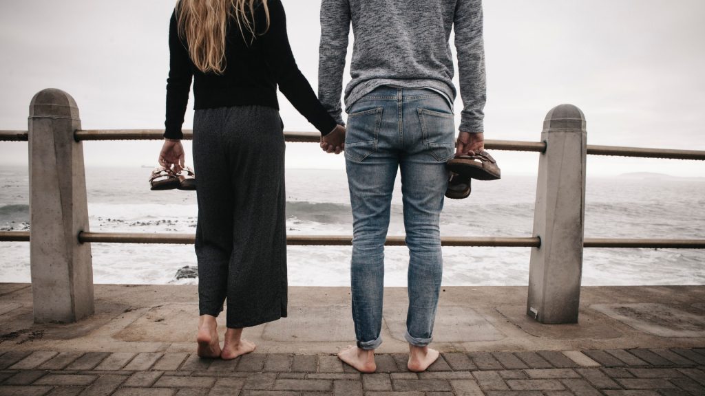 couple standing by fence at beach