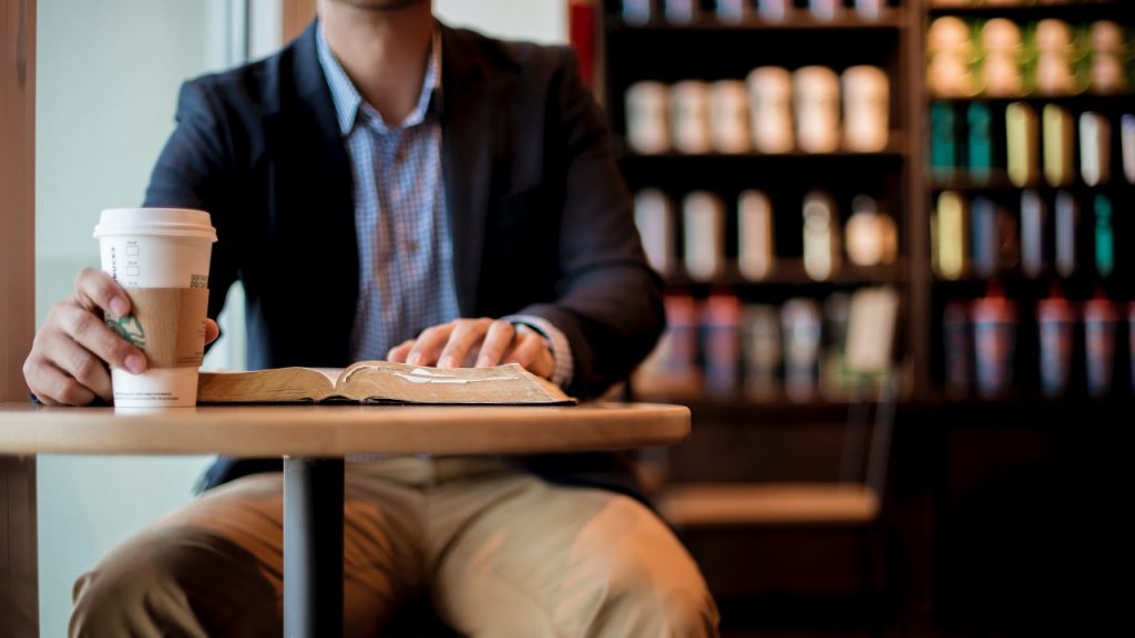 man sitting with bible at starbucks