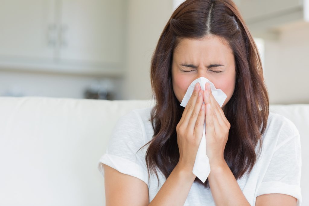 Brunette sneezing in a tissue