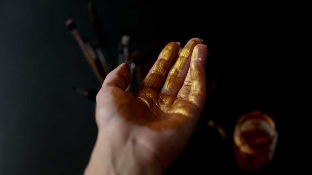 person's hand with gold paint on it
