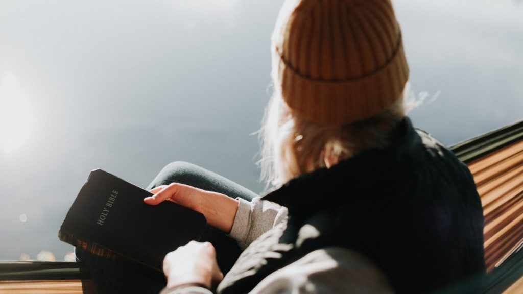 woman overlooking lake with bible in hand