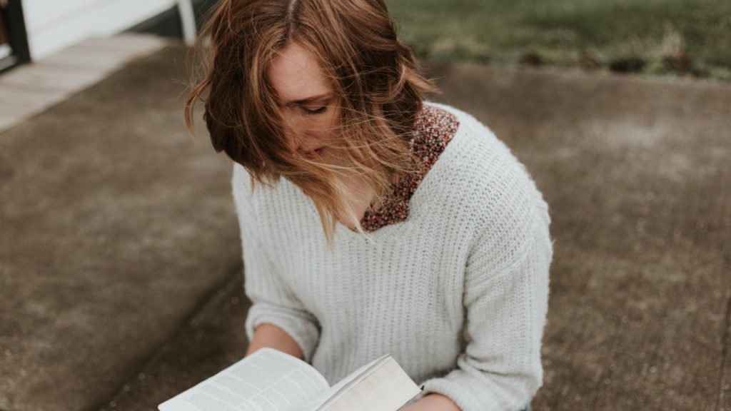 woman reading book praying