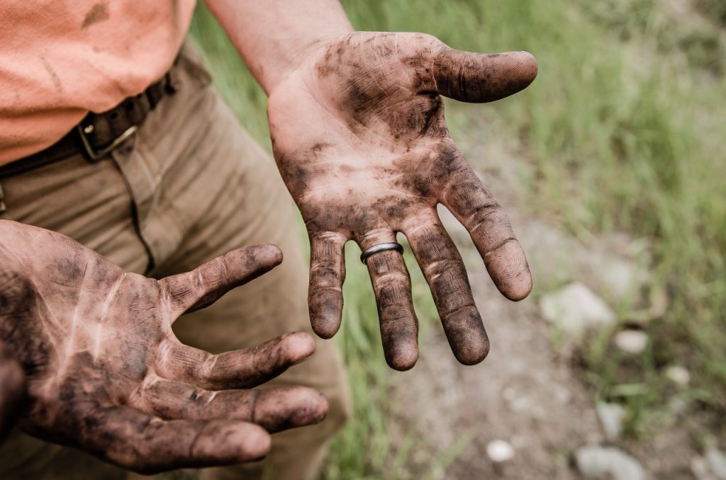 a man's hands covered in dirt