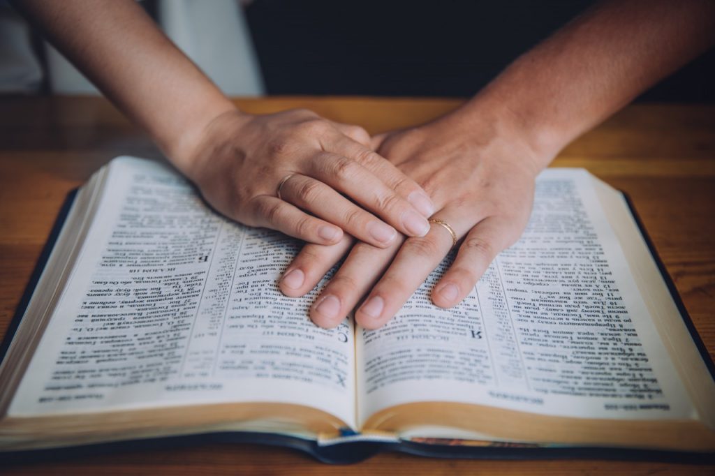Married couple putting hands on Bible