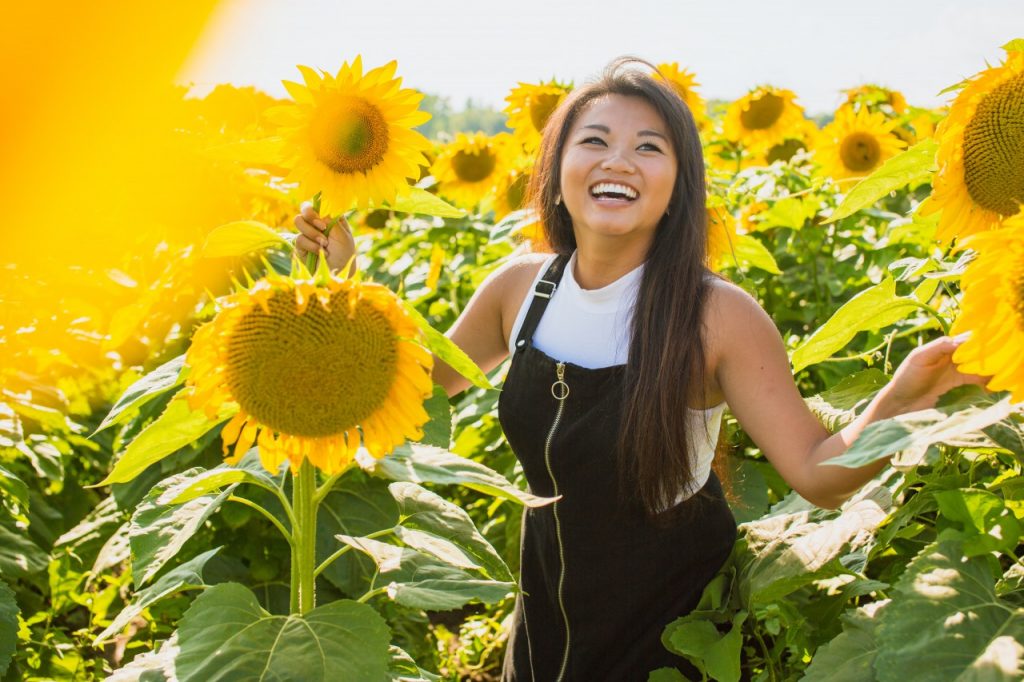 woman in a sunflower field laughing