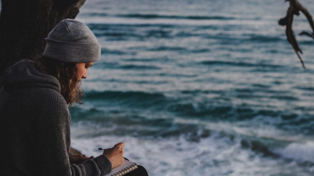 woman journaling at beach