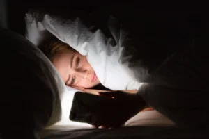 a woman in bed presumably looking at pornography on her phone