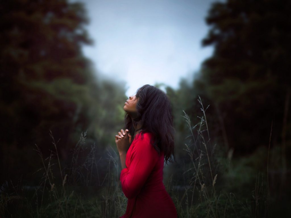 Woman in red dress praying outside