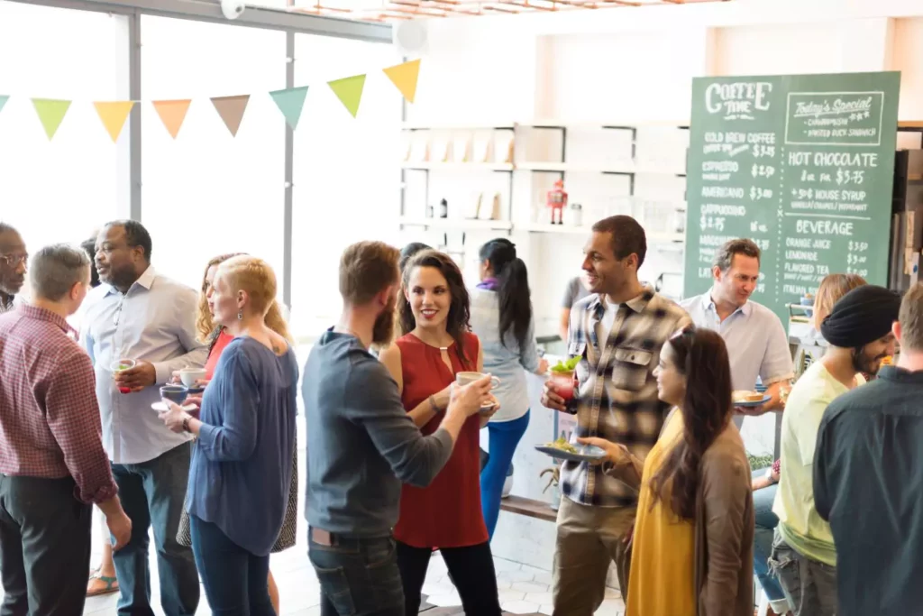 lots of people standing and talking at a coffee shop