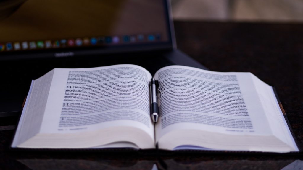 Bible on table with laptop