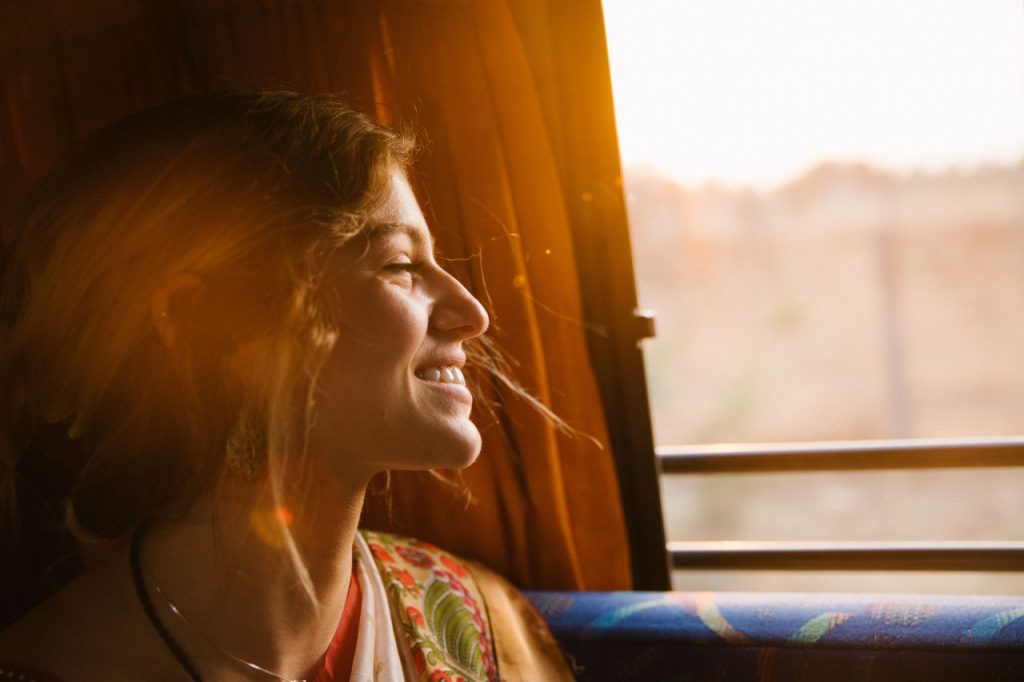 Woman smiling looking out window at golden hour