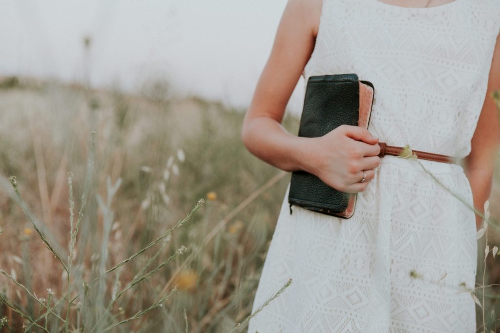 woman in field holding bible