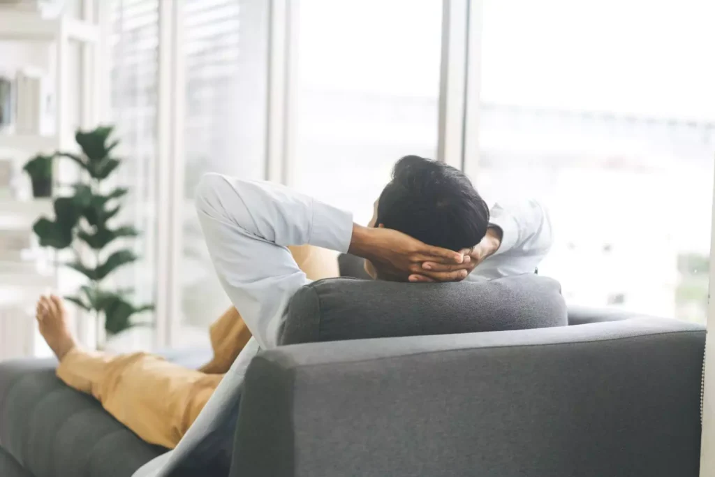 man lounging on a couch looking out of a window. Reasons why men don't pursue women