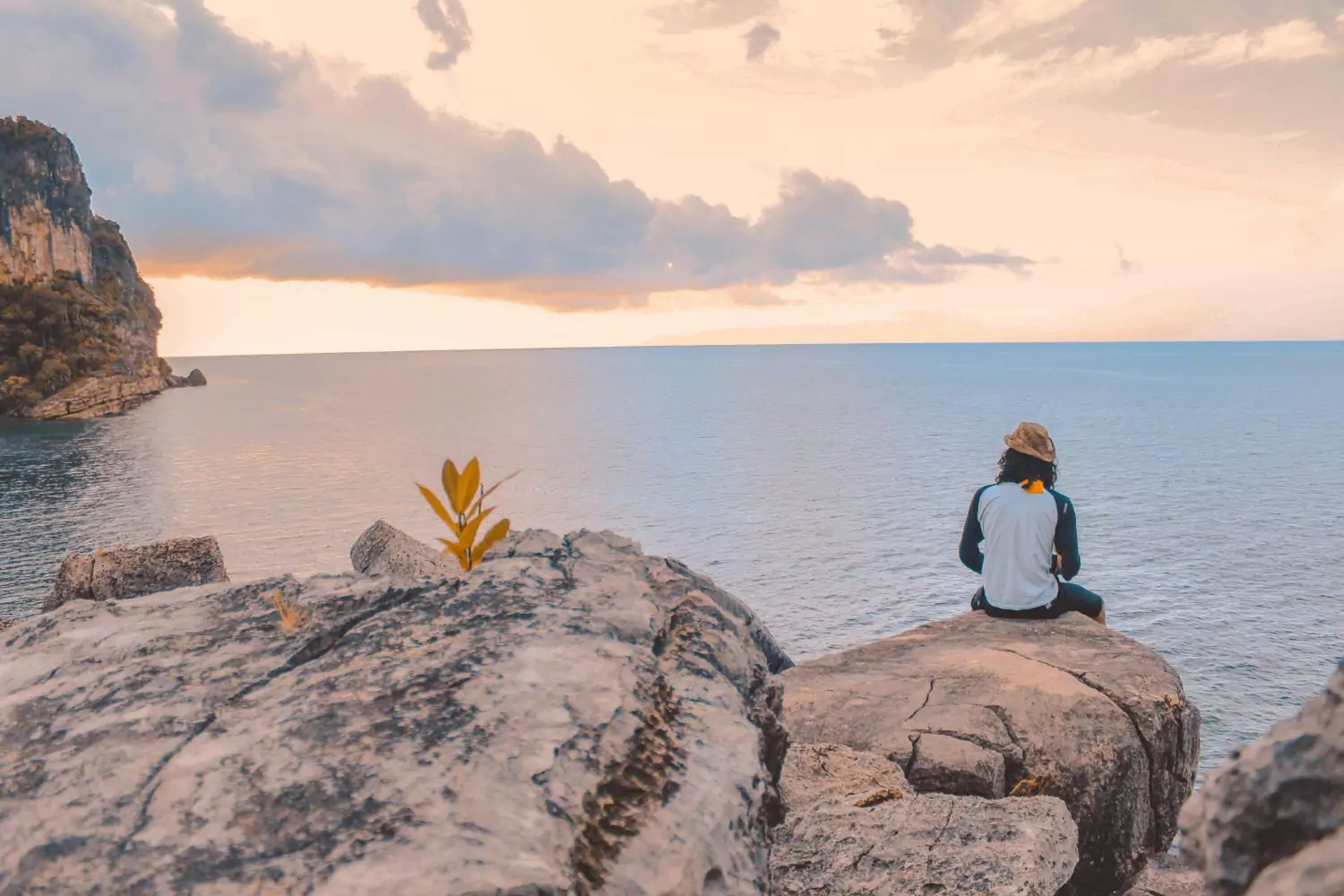 a man sitting on a cliff thinking about serving others