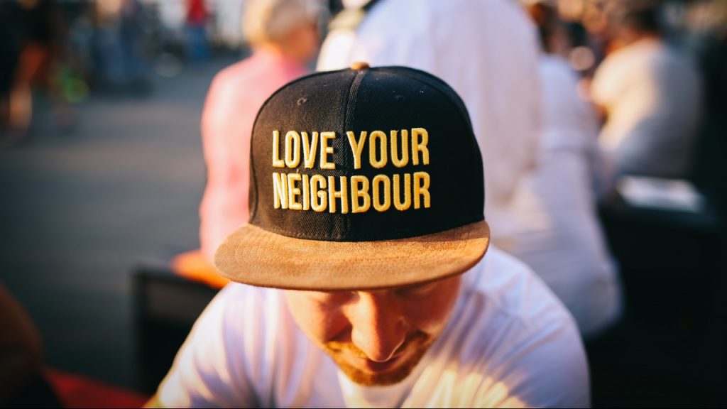 man wearing "love your neighbor" hat