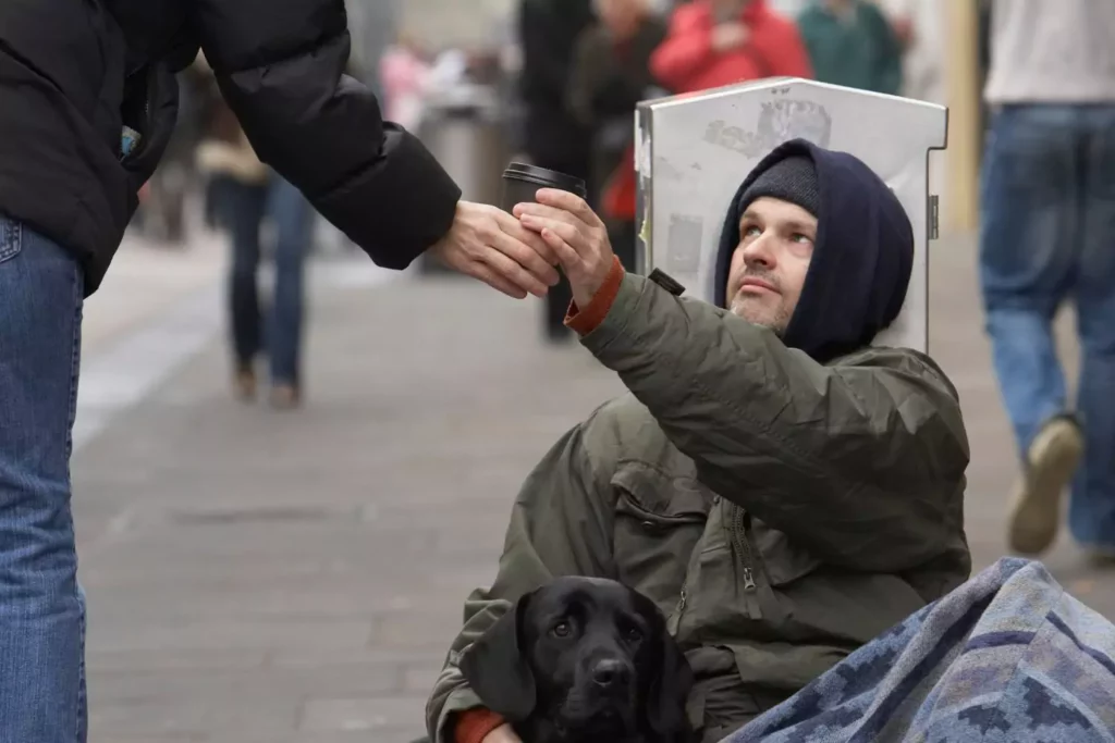 homeless man receiving coffee from a passerby - not being judged