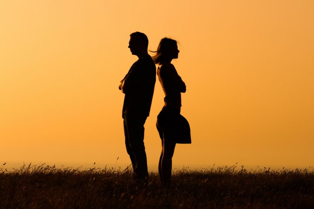 silhouette of man and woman standing back to back