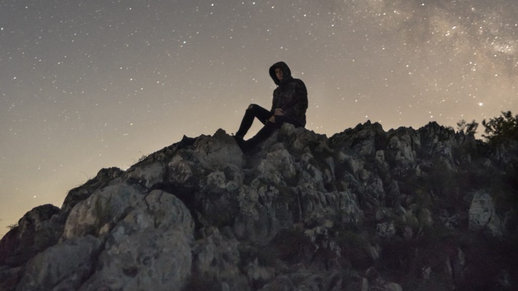man sitting on mountain at night