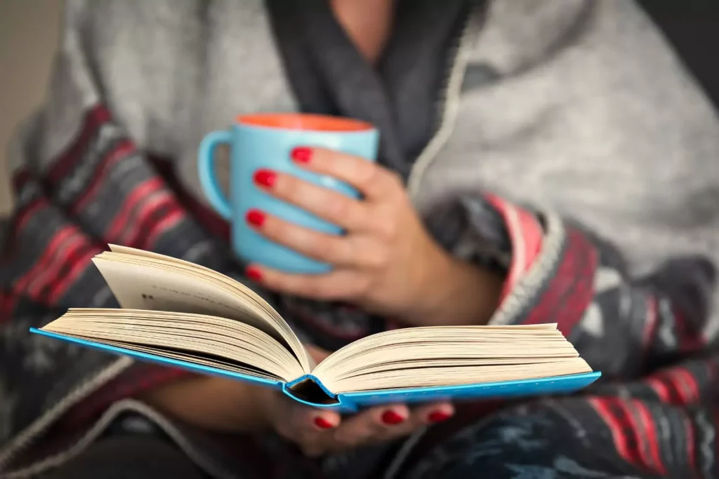 a woman holding a coffee mug and reading a book
