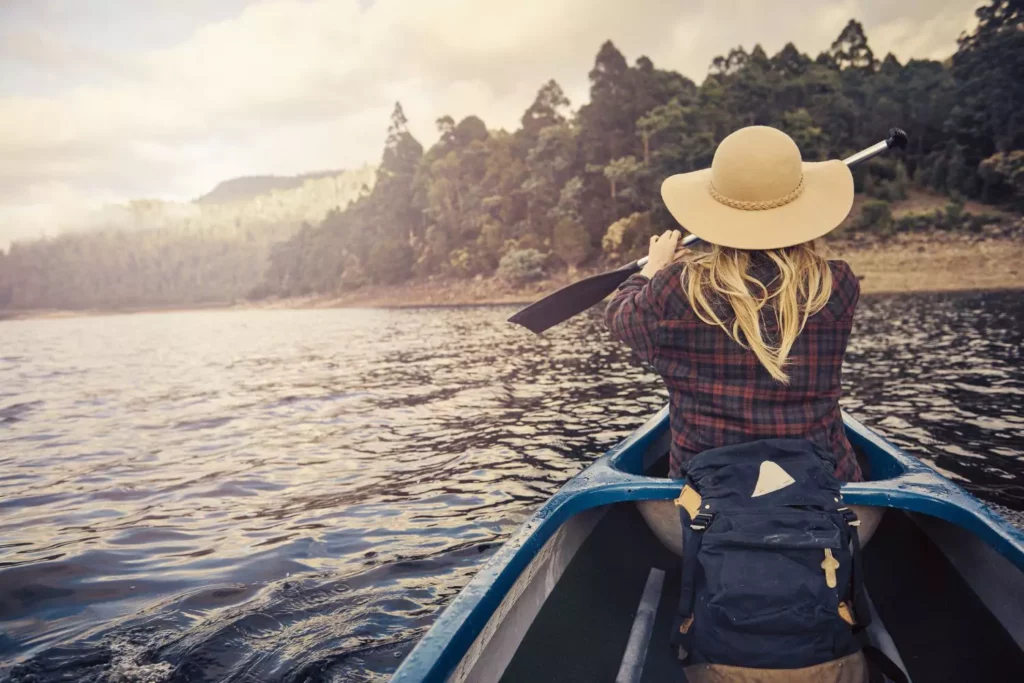 woman rowing a boat on a calm lake. vulnerable in her relationships