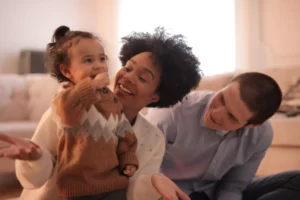 a mixed race couple playing with their young daughter - why have babies?