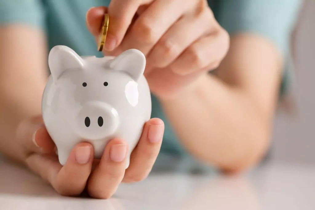 a person putting a coin into a piggy bank, working to pay off debt