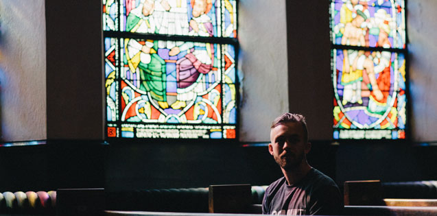 man sitting in sanctuary by stained glass window