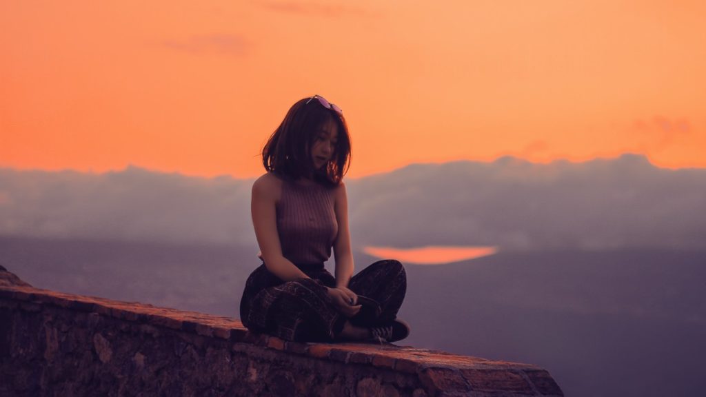 woman sitting on wall during sunset