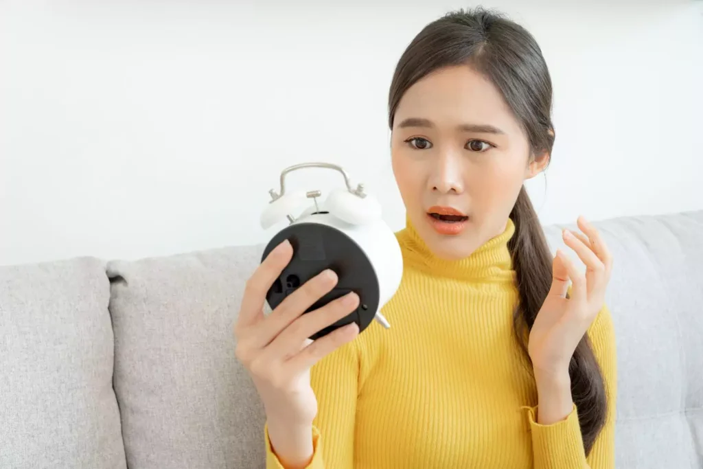 woman looking at an alarm clock worried about the future