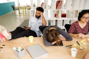 people at work, one with their feet on the table and playing on their phone
