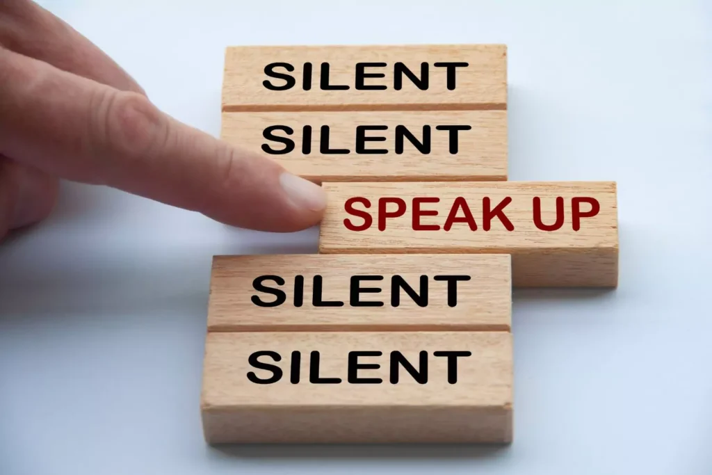 Blocks with the words silent and speak up on them, the speak up one being pushed forward