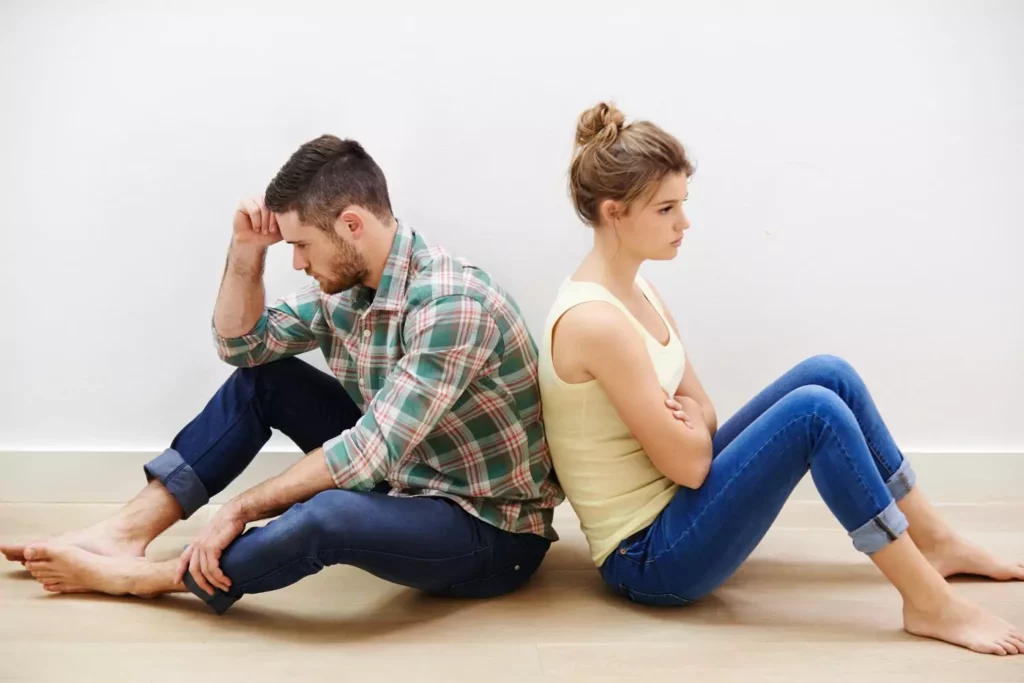 man and woman sitting on the ground back to back stuck in a bad marriage