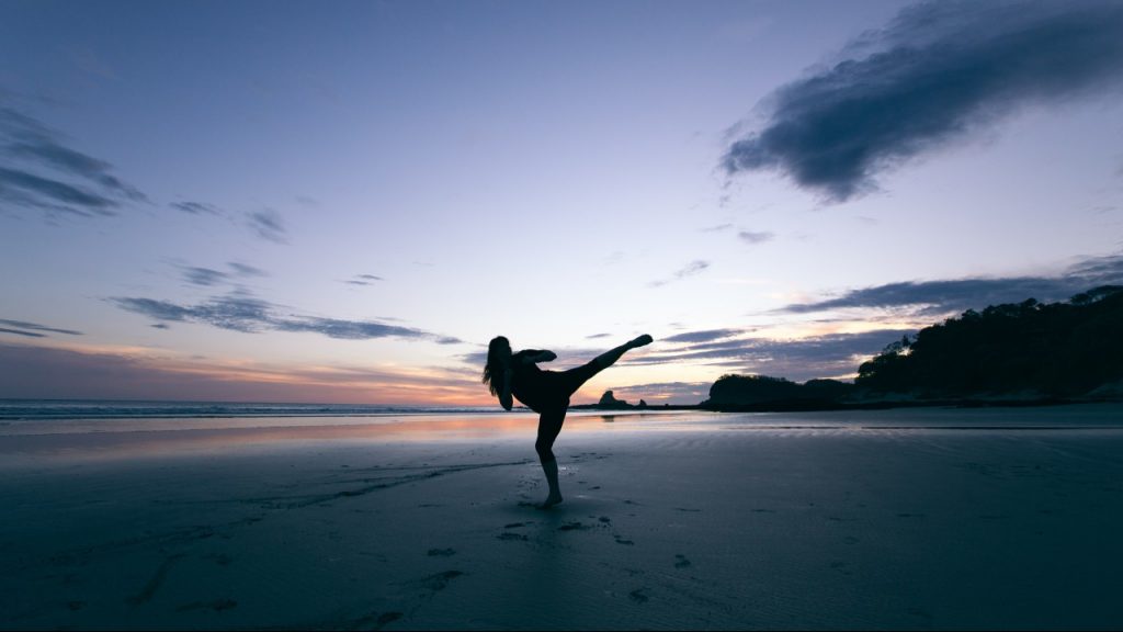 woman kicking on a beach during sunrise