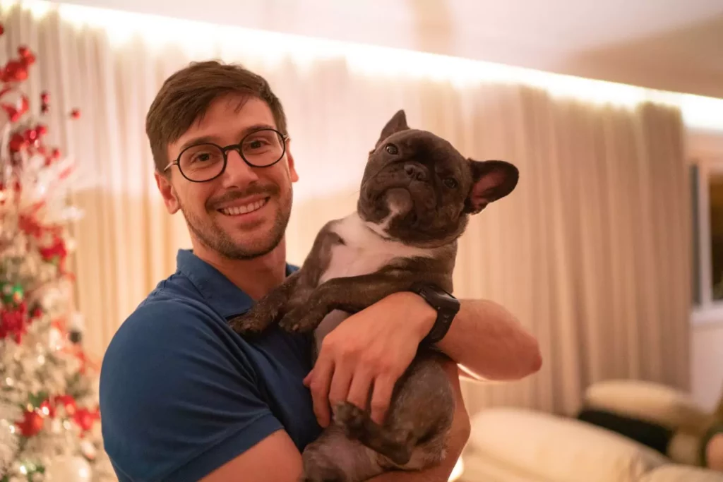 Guy holding his dog in front of a Christmas tree. Christmas loneliness