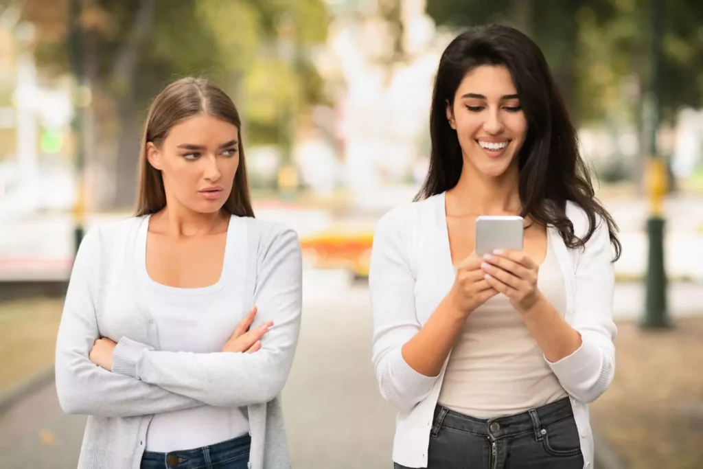 one girl annoyed by her friend being on her phone