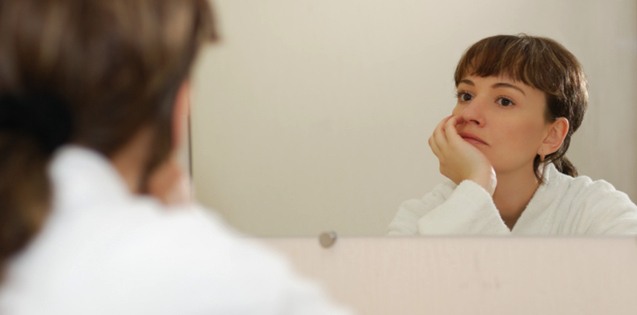 woman looking contemplatively in mirror