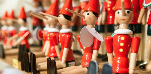 Several wooden Pinocchio figures sitting on a shelf