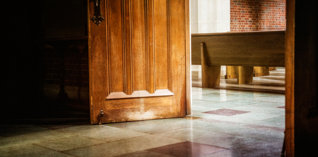 Open doors of a church leading to a pew