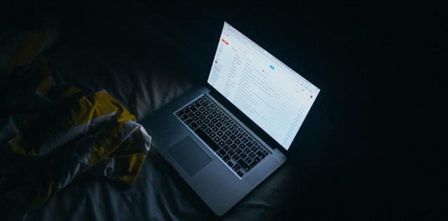 Laptop sitting on a bed in a dark room