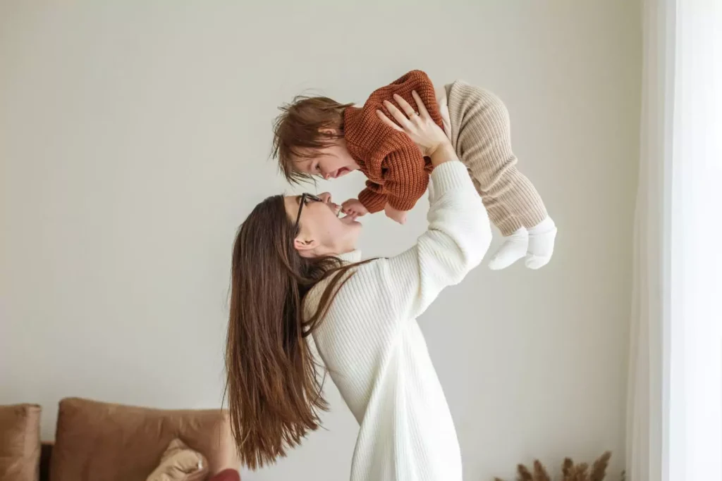 a woman holding a baby in the air - I feel like I was made to have babies