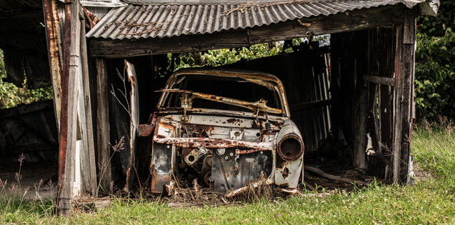 a broken down old car sits in a garage