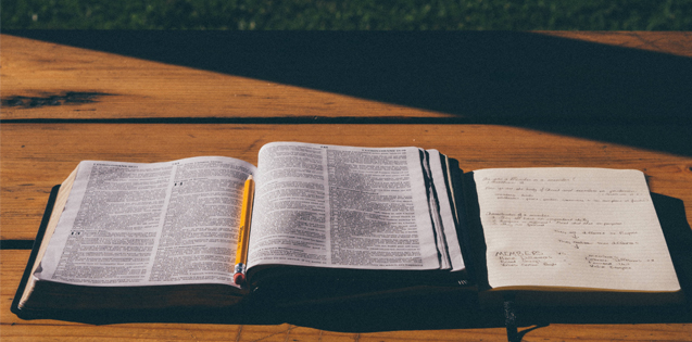 Open Bible and notebook sitting on a table