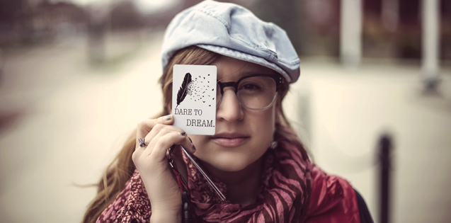 A girl holding a "dare to dream" card