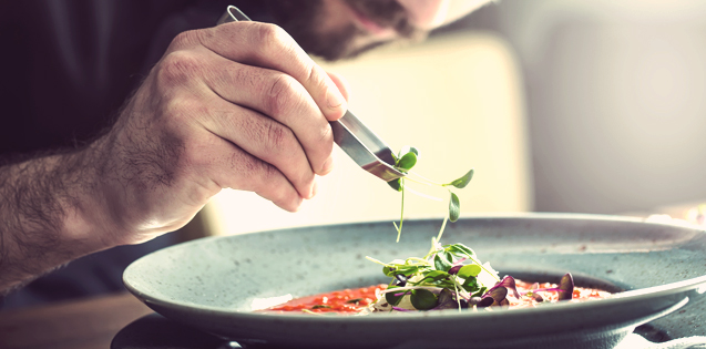 A chef adding garnish to soup